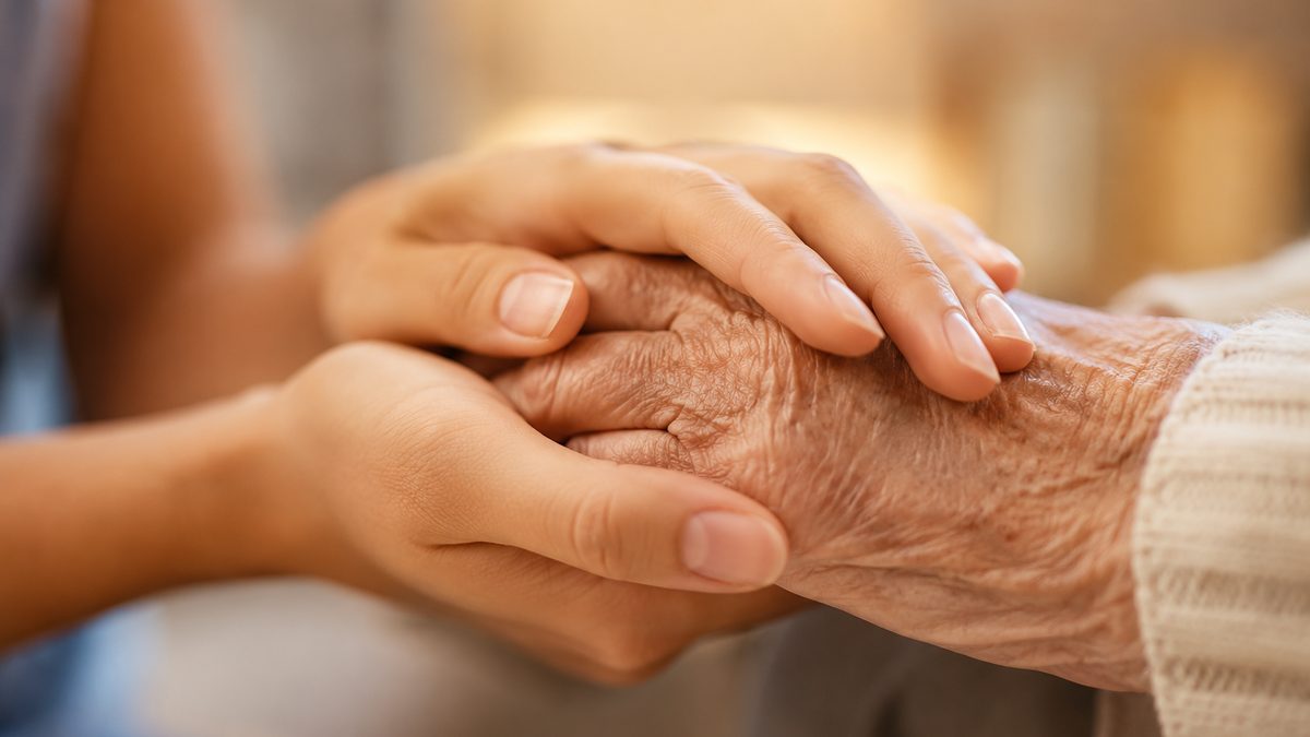 A caregiver gently holding a senior's hands in a calm, reassuring moment.